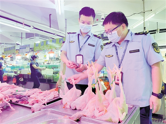 市场监管部门工作人员对农贸市场售卖的禽类开展溯源检查。