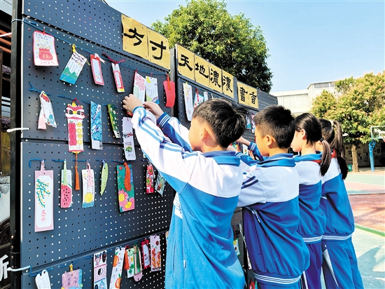 该校举办“巧手成签”书签制作比赛，学生们将制作好的书签挂上展示区。