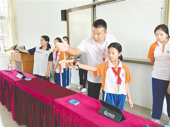 学生正屏息凝神，手持光电模拟训练枪进行射击练习。