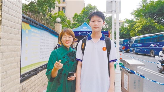 身着绿色旗袍的李女士与儿子合影。
