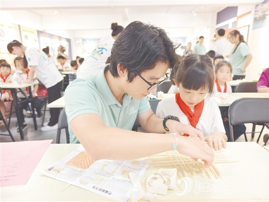 学生志愿者耐心教导孩子制作手工。