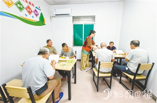 老人在助餐点享用热气腾腾的饭菜。