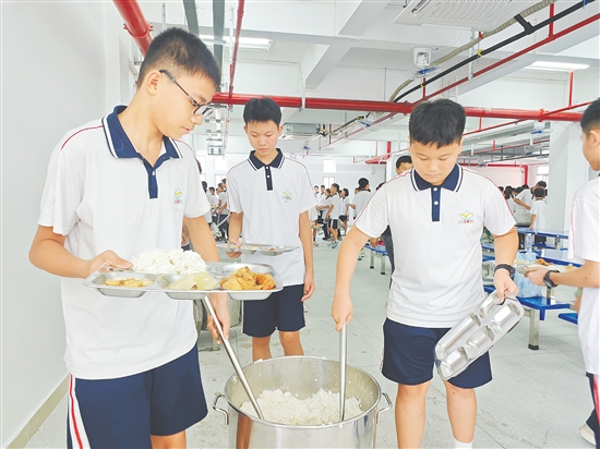 在鹤山一中附属中学，学生在崭新的饭堂有序打饭，该校精心设计菜谱，确保营养与美味兼备。