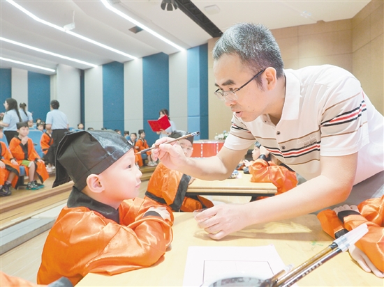 在朱砂启智环节，教师用毛笔在新生的额头点上红痣。