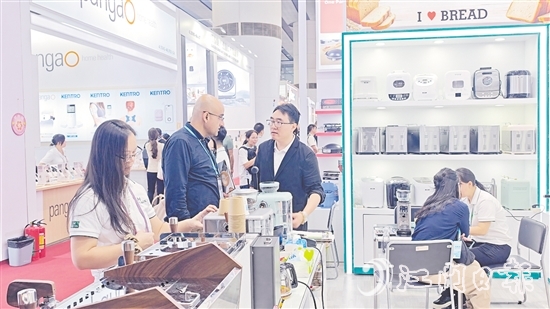 外国客商在一家蓬江区家电企业的展区前洽谈合作。任佳燕 外国客商在一家蓬江区家电企业的展区前洽谈合作。任佳燕