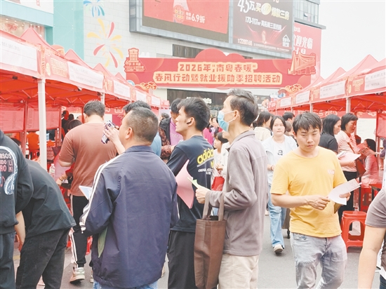 招聘会现场，求职者手持简历穿梭于企业摊位间。