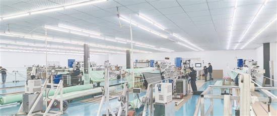江门鸿荣纺织研究院有限公司的生产车间内，一台台先进设备全速运转，工作人员正有条不紊地操作设备。