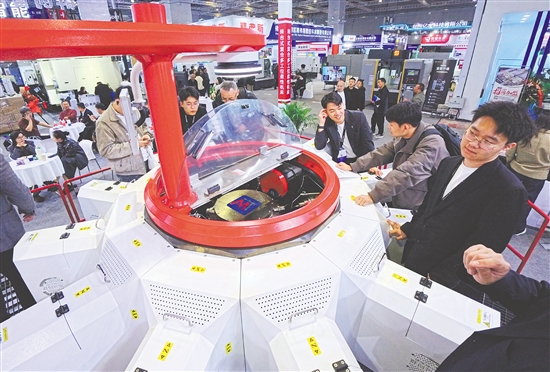 图为当日，参观者在一款转台式多工位柔性复合机床展品旁观看交流。新华社发