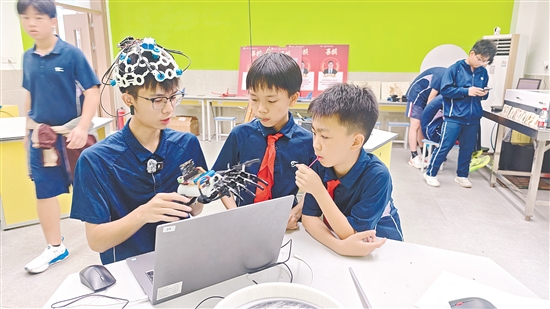 学生展示自主设计的仿生机械手控制系统。