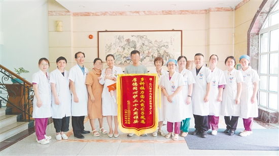 吴女士夫妇带着女儿回到医院，送上一面“周岁锦旗”。