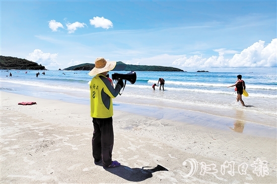 烈日下，工作人员守在沙滩上，提醒游客注意安全。