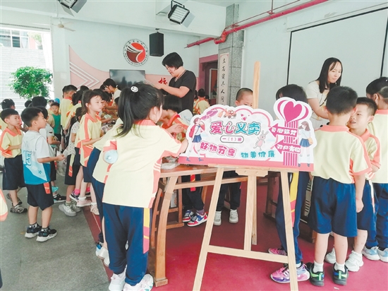 义卖现场，各摊位的叫卖声络绎不绝，“小摊主”认真介绍物品，“小顾客”细心挑选自己心仪的物品。