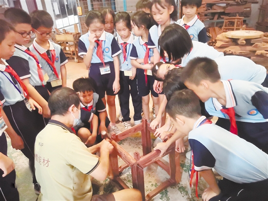 大江镇中心小学师生走进生产车间参观红木家具制作过程，感受红木家具的传统之美。