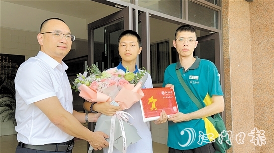 邮政部门工作人员为学子伍润龙（中）送上录取通知书。