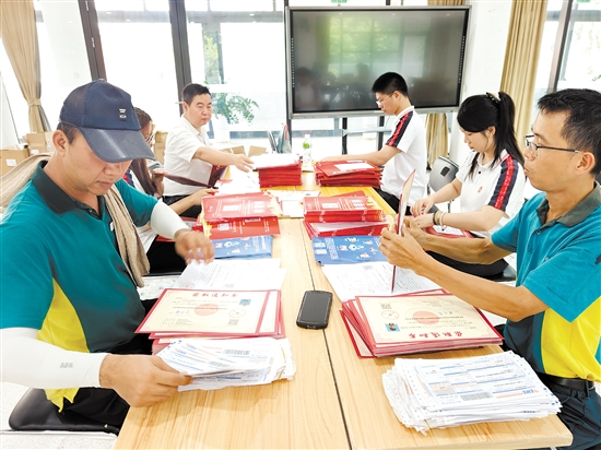 邮政工作人员和五邑大学学生志愿者正在封装录取通知书。