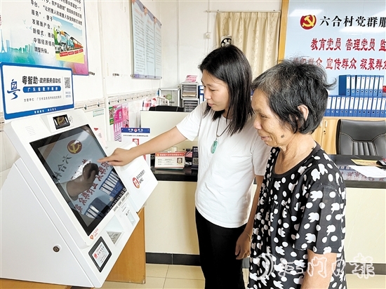 村委会干部在“粤智助”政务服务自助机上引导村民办理社保业务。