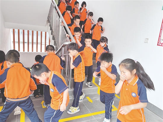 学生们弯腰低头、捂住口鼻，按照预定路线有序撤离。