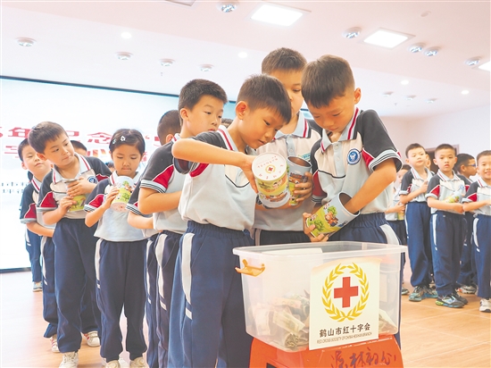 学生代表将爱心储蓄罐里的零钱投入捐款箱，汇聚点滴爱心。