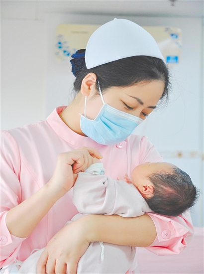 这是一双托起生命的手。江门市中心医院爱婴区主管护师汤玲玲正在安抚哭闹的宝宝。她一手环住襁褓，一手牵起宝宝的小手，动作舒缓而温柔。在这里，生命的啼哭与温柔的守护相遇，汇聚成世间至暖的力量。（林锦棠