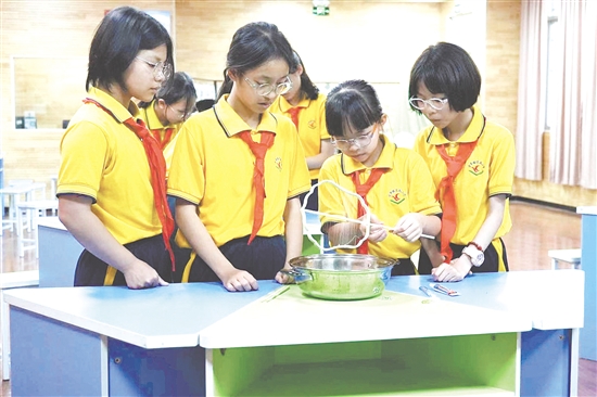 劳动课上，学生们分工协作，学习制作蚕丝扇。