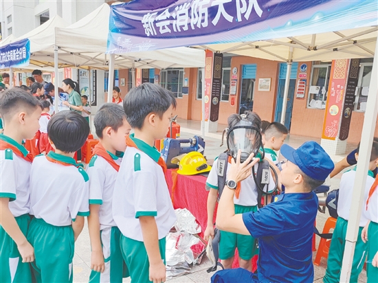 在消防救援大队的展示区，同学们体验了消防员的空气呼吸器等装备。