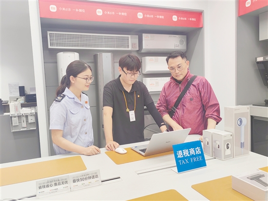 税务部门辅导小米之家工作人员为旅客开具退税申请单。