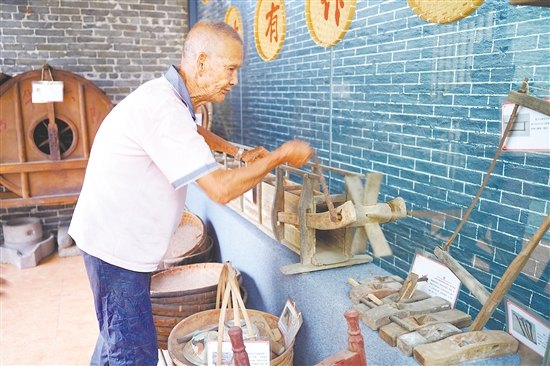 新华村打造农耕文化展馆，留住乡村记忆。图为村中老人向记者介绍农具。