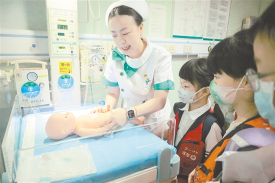 医护人员为小记者演示新生儿辐射保暖台的用途。 医护人员为小记者演示新生儿辐射保暖台的用途。