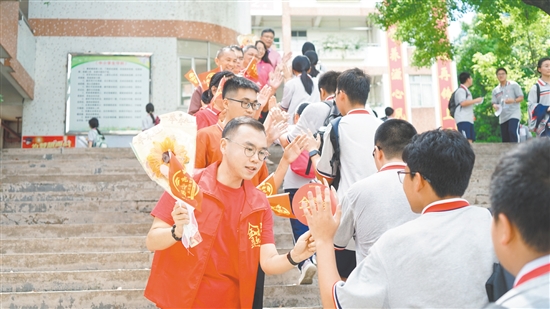 在景贤学校考点，老师们手持向日葵和小红旗为考生加油。