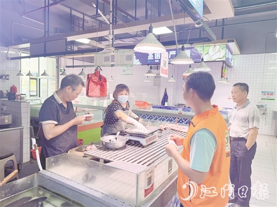 买菜易的平台接单员李叔（橙色马甲）正在鱼摊旁等待取单。