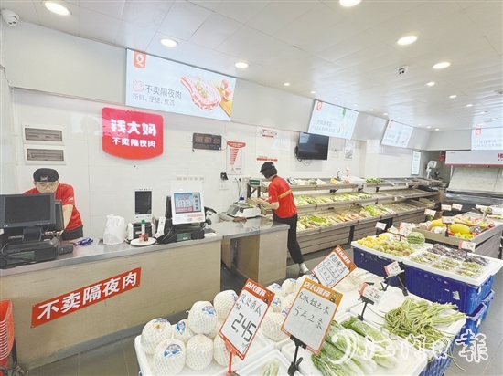 钱大妈生鲜店的工作人员正在线上接单并准备菜品。
