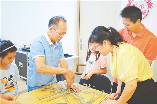 孩子和家长在手艺人的指导下学习编织小竹筐。