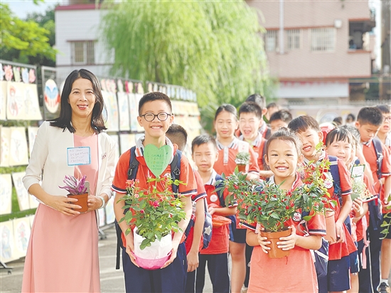 新民小学同学们各自手捧暑假期间的种植成果返校。