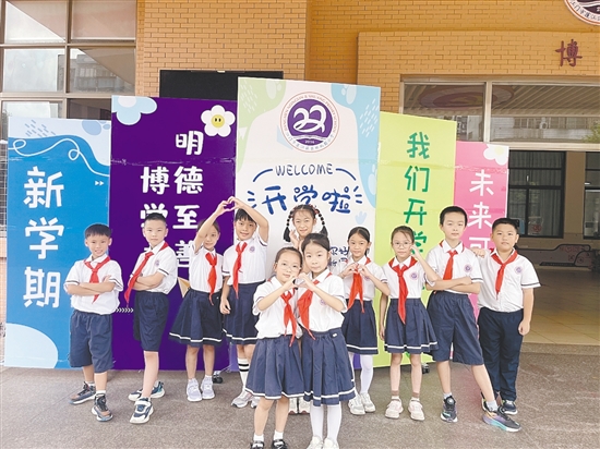 开学首日，农林双朗小学的学生们在学校精心准备的背景板前留影。
