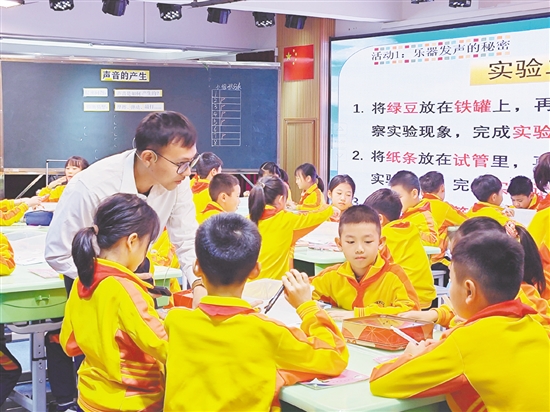 教师指导学生用橡皮筋、铁罐、试管模拟乐器发声。