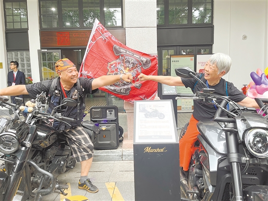 珍姨（右）坐在机车上与其他人碰拳互动。