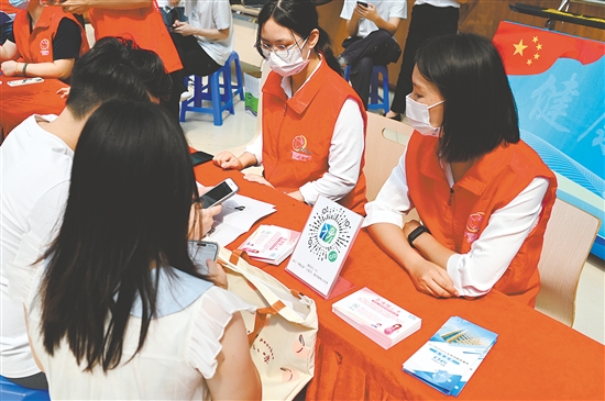 工作人员向市民介绍职工生育保险待遇。