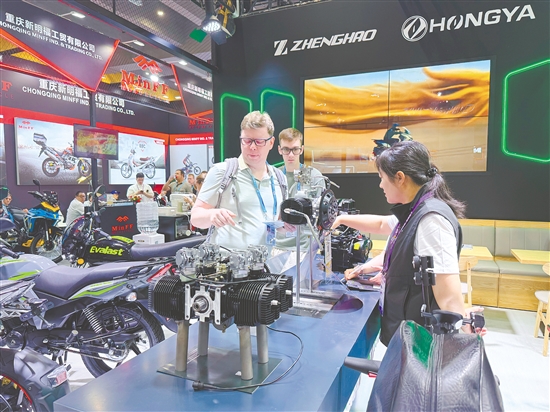在正豪摩托展位，工作人员为外国客商介绍摩托车零部件。