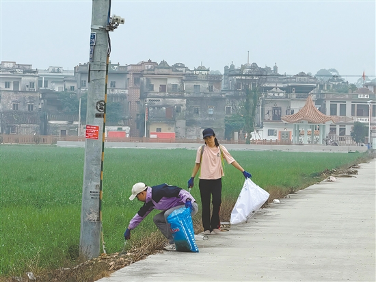 新村民走在乡村道路清理垃圾。