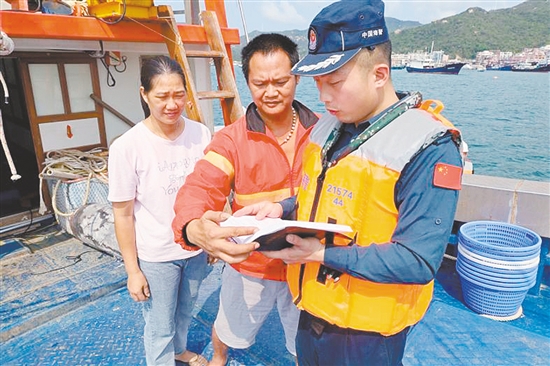江门海警局执法员登上渔船，开展休渔期普法宣传教育工作。
