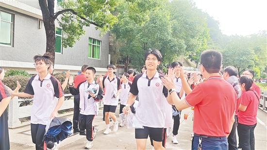 在台山市华侨中学考点，穿着红色衣服的老师们夹道送考，与考生逐一击掌。黄颖欣