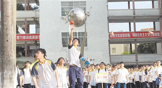 恩平市华侨中学校园广场悬挂着3只“粽子”，路过的考生们纷纷踮脚跳跃，抬手触碰“粽子”，取“高中”美意。梁晓敏
