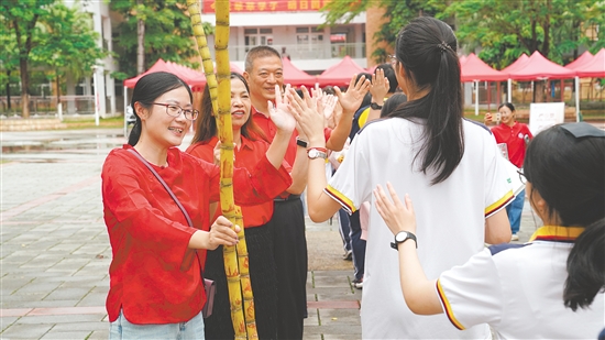 老师们手持甘蔗和学生们击掌，寓意考试“掂过碌蔗”。