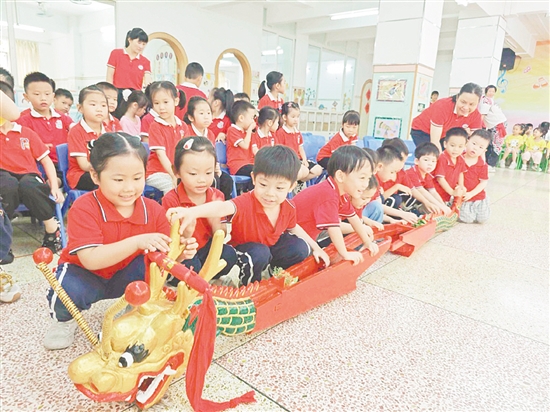 在长安幼儿园，小朋友们与龙头、龙尾互动。