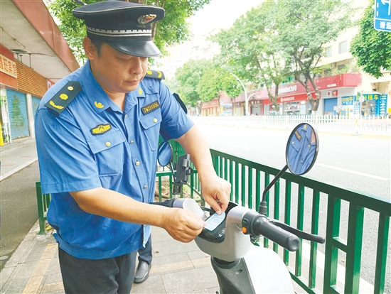 执法人员将违停车辆停好后，张贴温馨提示，引导市民规范停车。