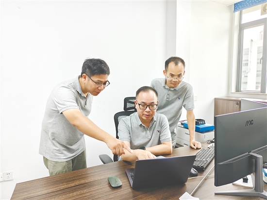 李海全（中）与团队成员讨论技术参数。