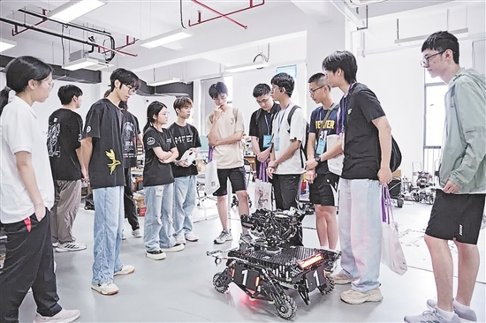 在邑大IMCA机器人战队实验室，战队自研机器人吸引学员们驻足围观。