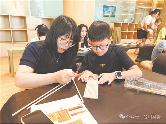 孩子在家长的陪同下动手拼装桥梁模型。