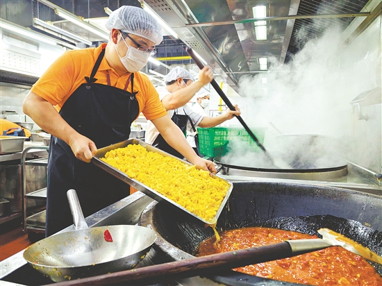 林郁周在食堂后厨与其他员工一起做饭。