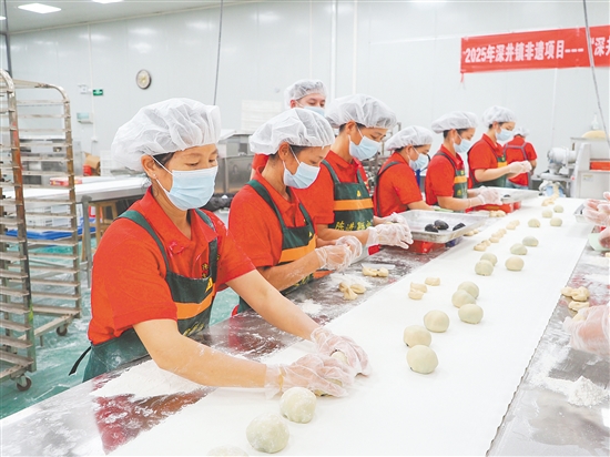 在生产车间，工人们用手工方式擀饼皮、包馅料。